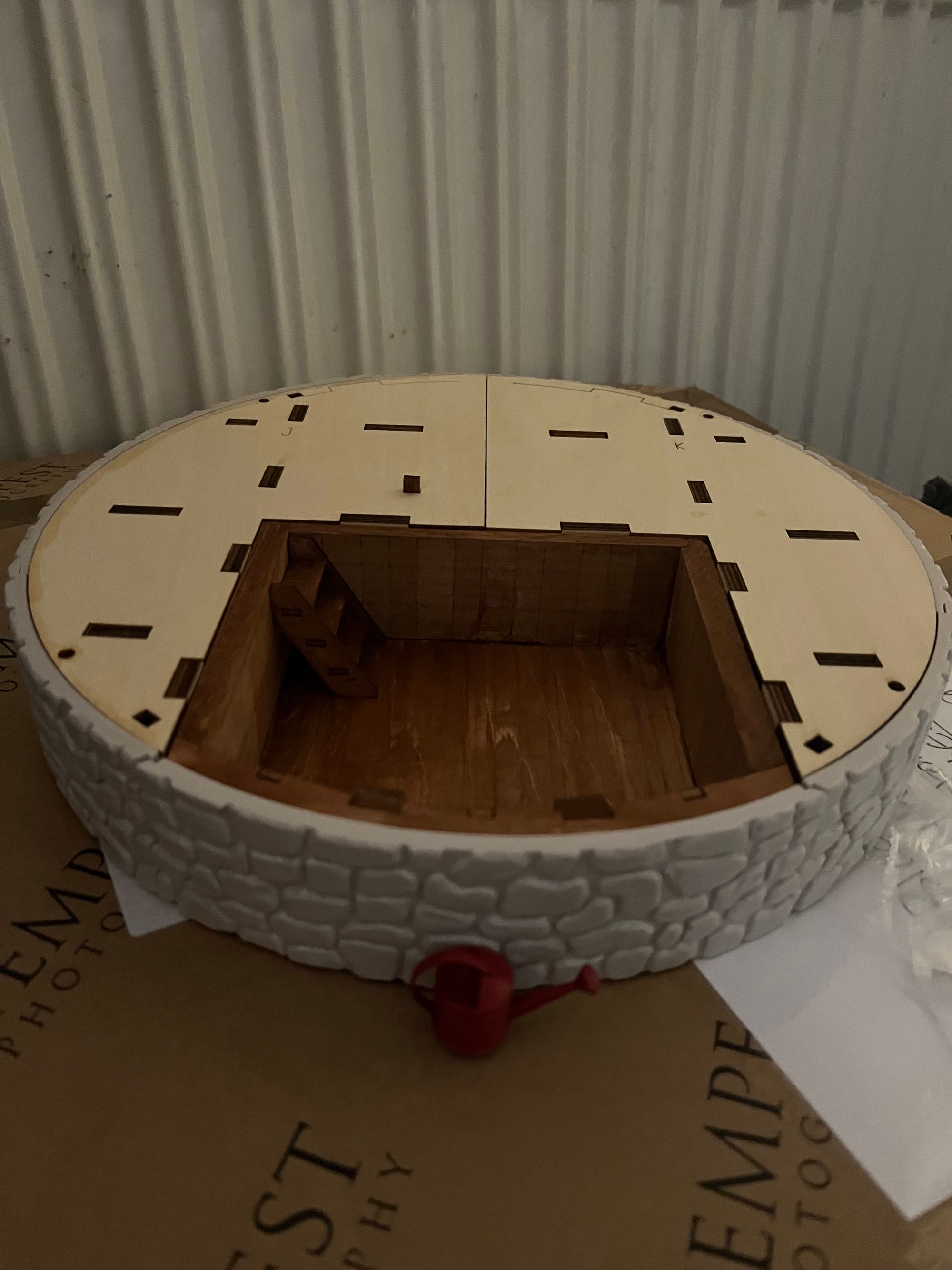 A circular basement with a drawer opened with a small red watering can.
